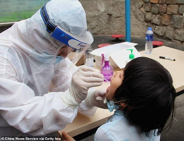 Медик берет мазок у ребенка для теста на коронавирус в общине Урумчи