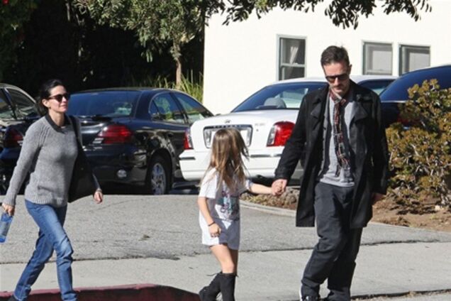 Кокс с семьей идет к авто. Фото