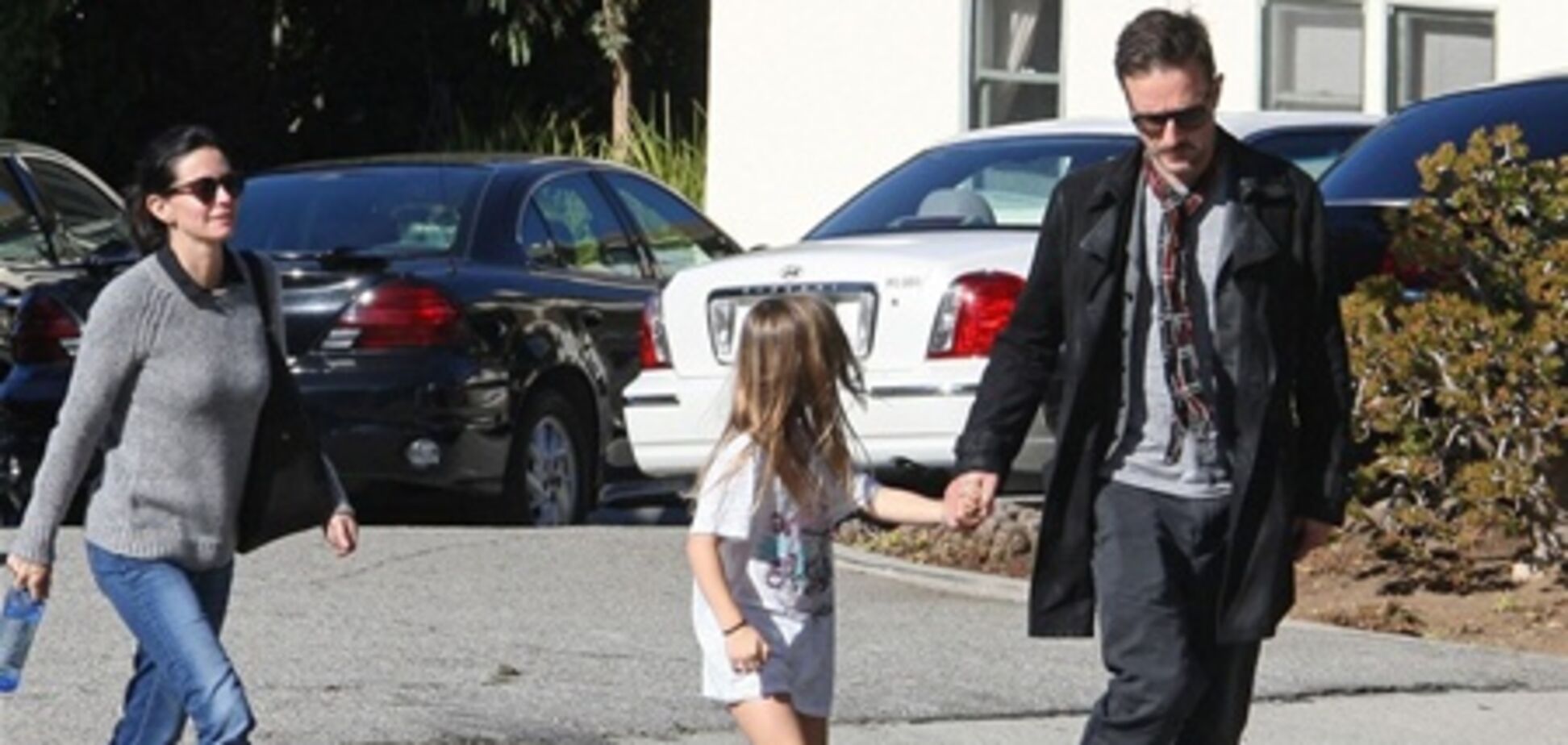 Кокс с семьей идет к авто. Фото