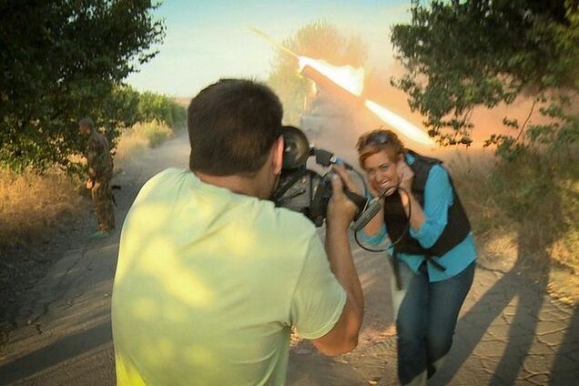 Журналистка RussiaToday с улыбкой позирует на фоне стреляющего 'Града'