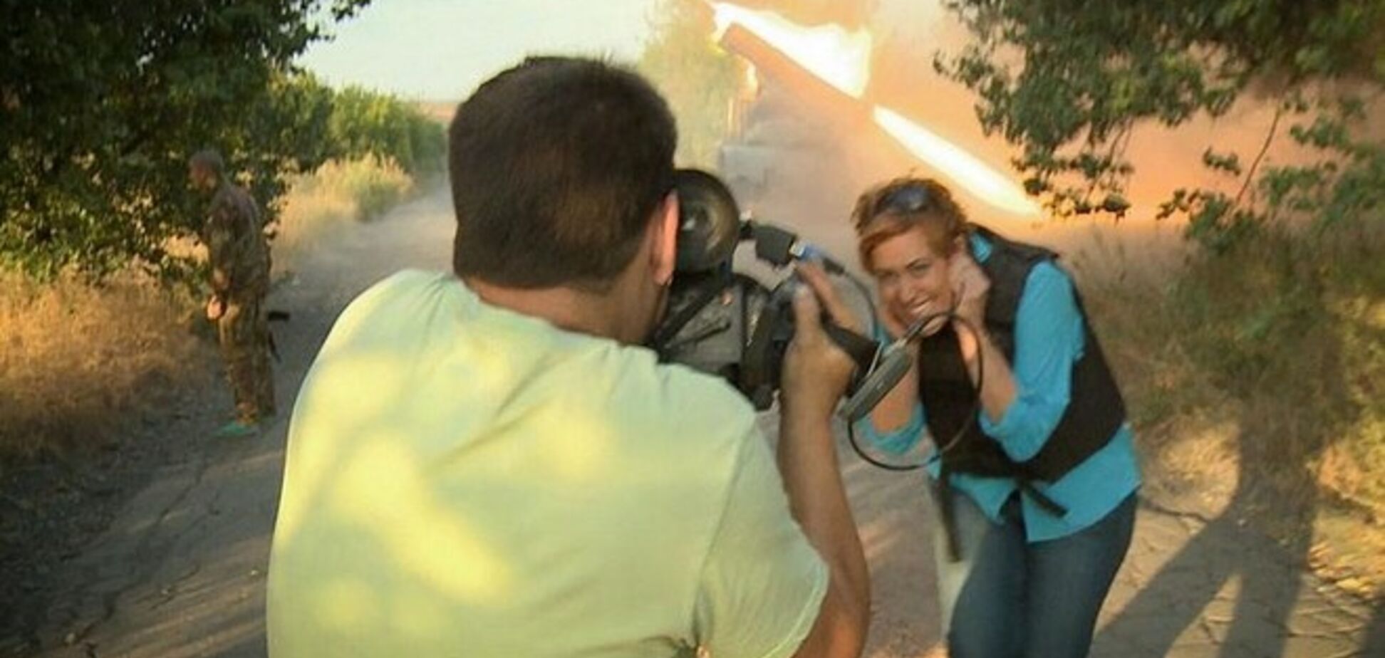 Журналистка RussiaToday с улыбкой позирует на фоне стреляющего 'Града'