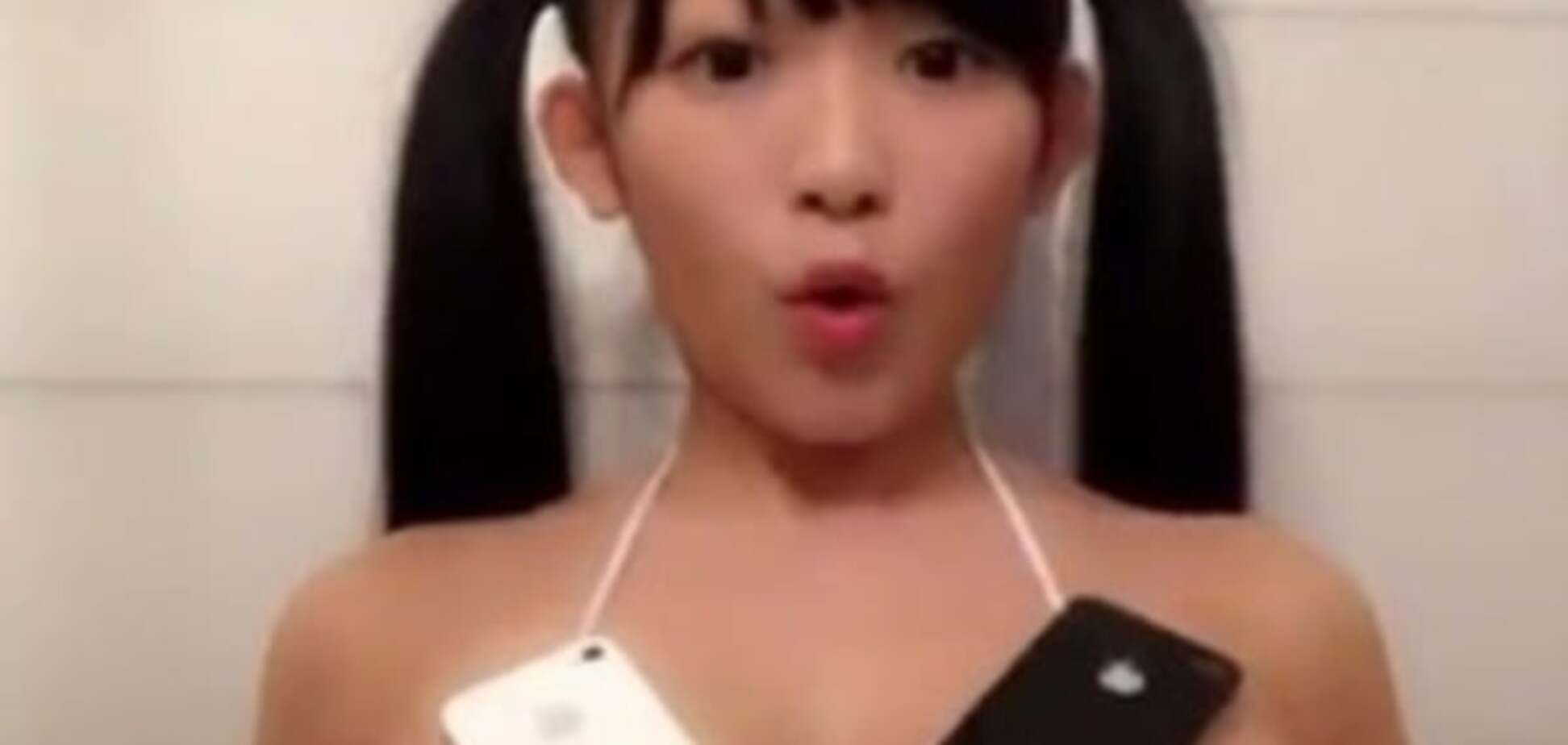 Азиатская девушка балансирует смартфонами на груди