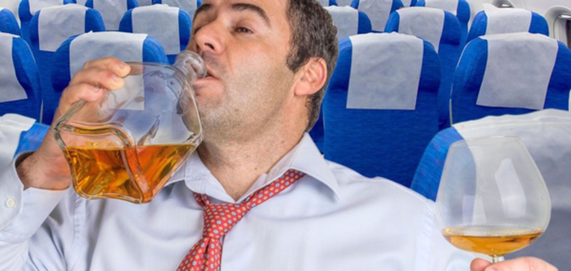 мужчина пьет алкоголь в самолете