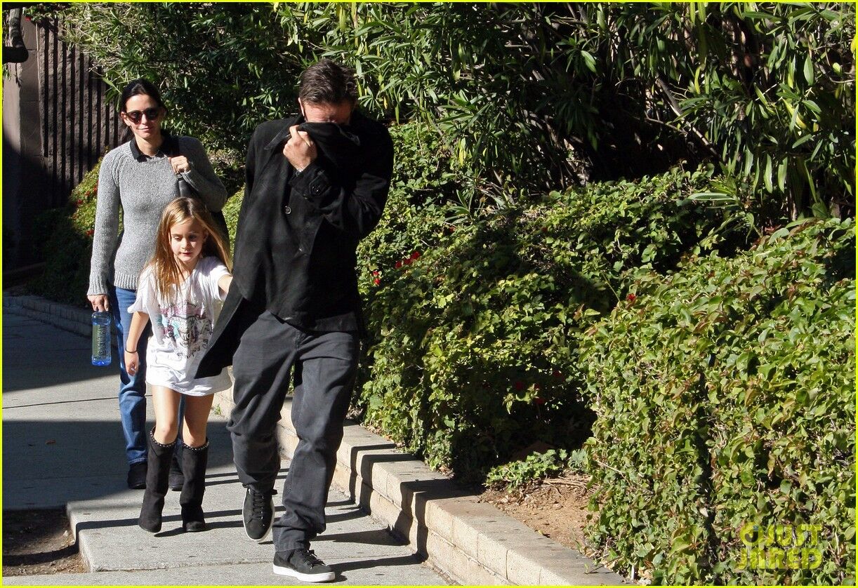 Кокс с семьей идет к авто. Фото