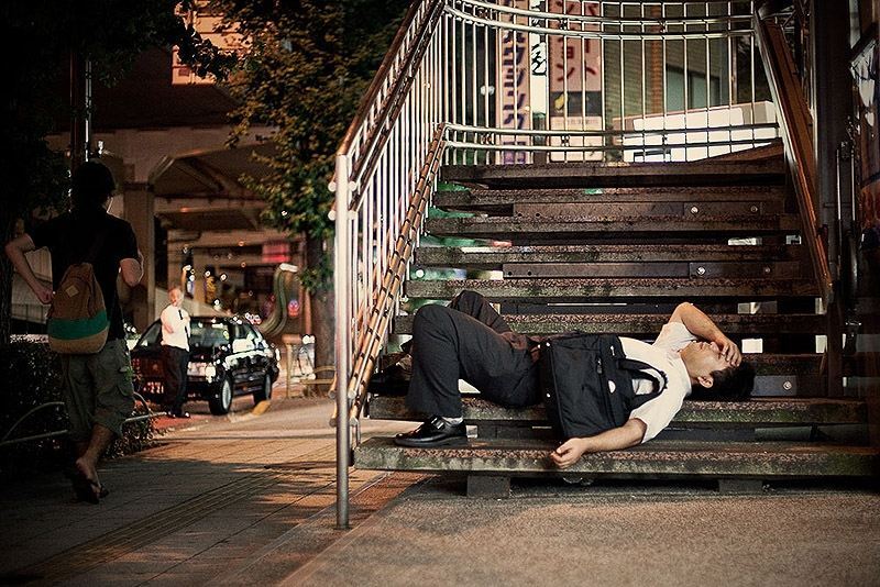 Изнуренные работой жители Токио, спящие на улице