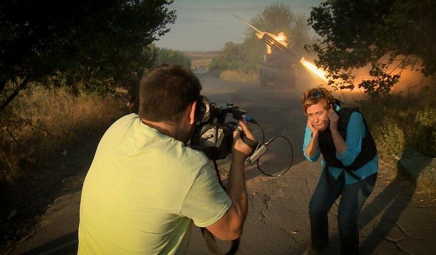 Журналістка RussiaToday з посмішкою позує на тлі стріляючого "Граду"