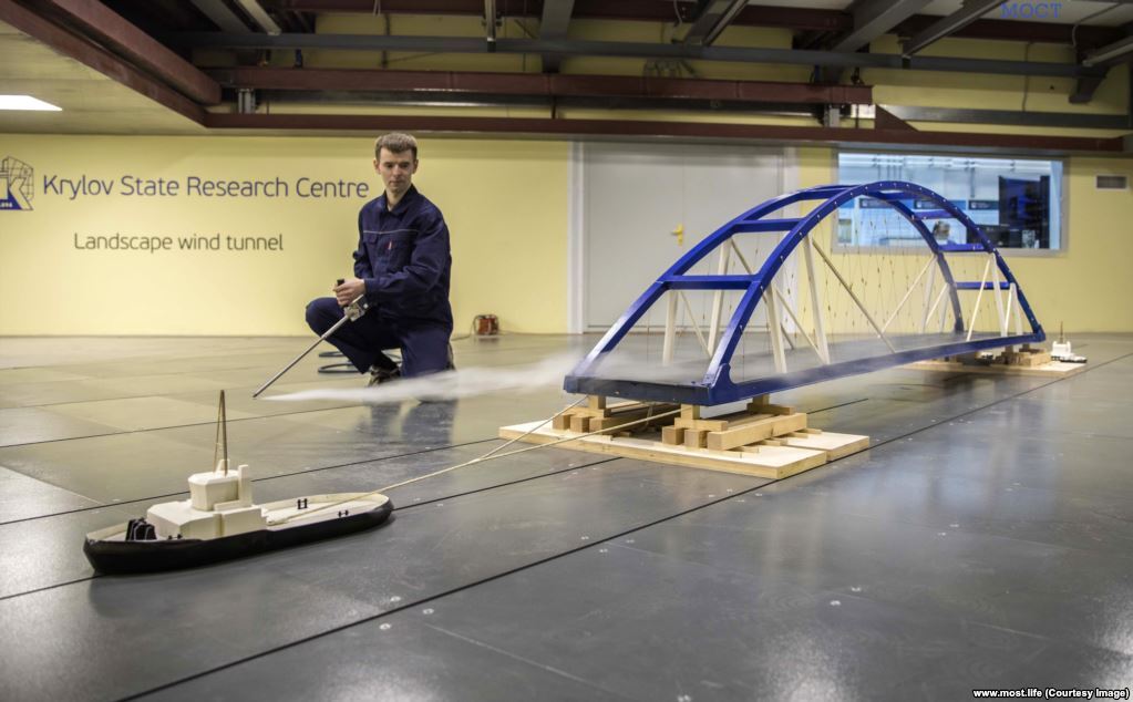 Інженер спостерігає за масштабною моделлю буксирів моста через аеродинамічну трубу