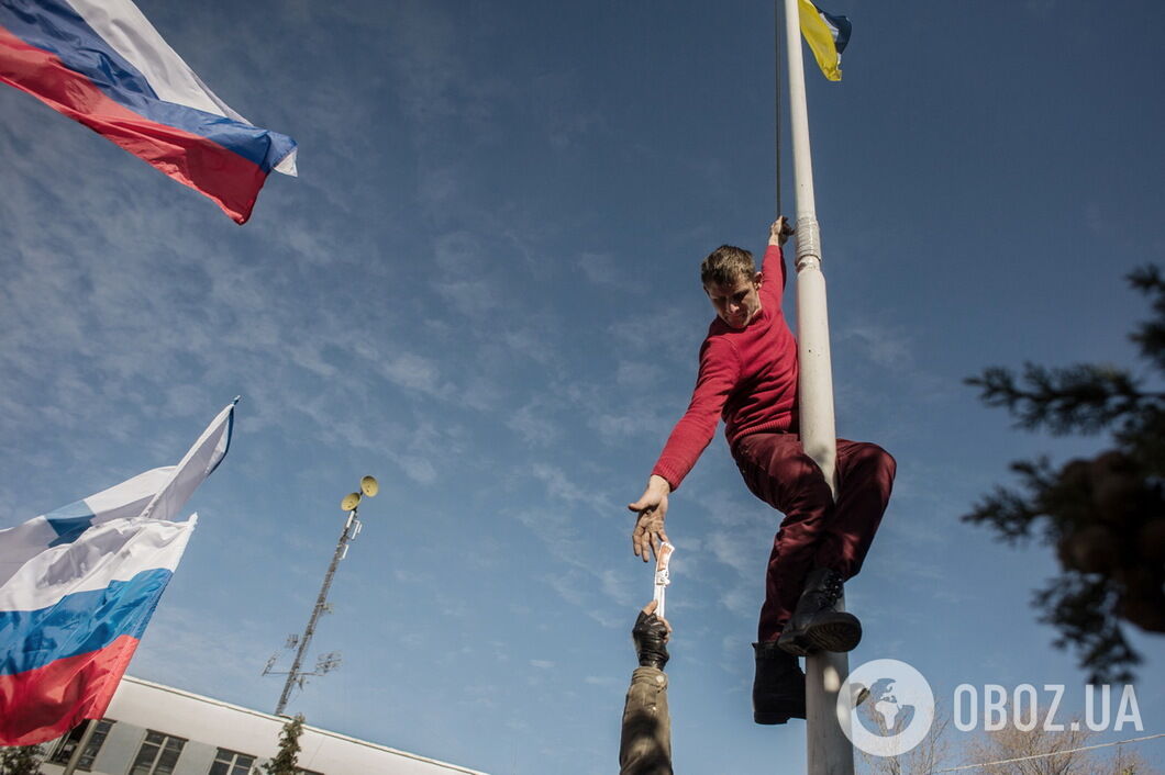 Один из участников захвата штаба ВМС Украины в Севастополе срезает с флагштока Украинский флаг. 19 марта 2014 года