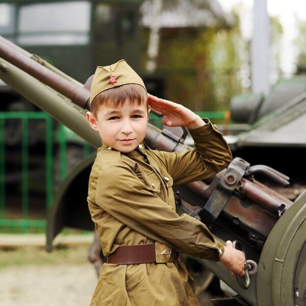 Мальчик в военной форме рядом с пушкой на День Победы