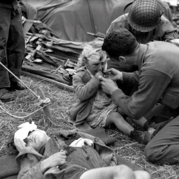 Американские медики и раненая французская девочка Женевьев Мари (Geneviève Marie) в полевом госпитале на ферме Ла Усе (La Houssaye).
