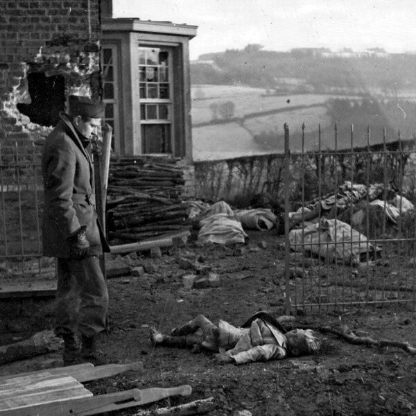 Американский солдат у тела убитого немцами в Ставело (Stavelot) бельгийского мальчика. На заднем плане видны тела других расстрелянных мирных жителей.