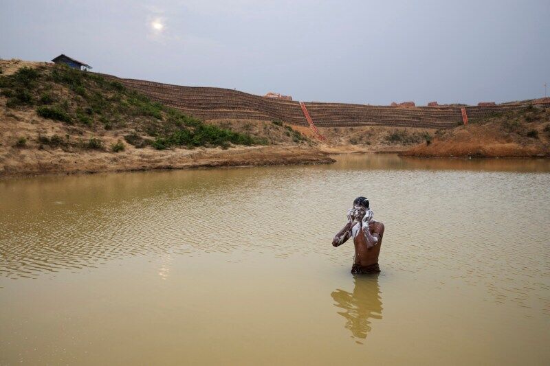 Чоловік з етнічної групи Рохінджа купається в штучному ставку біля табору, де живе
