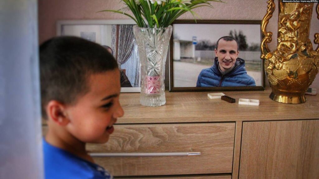 Сын Сервера Мустафаева Юнус возле фотографии отца в своем доме