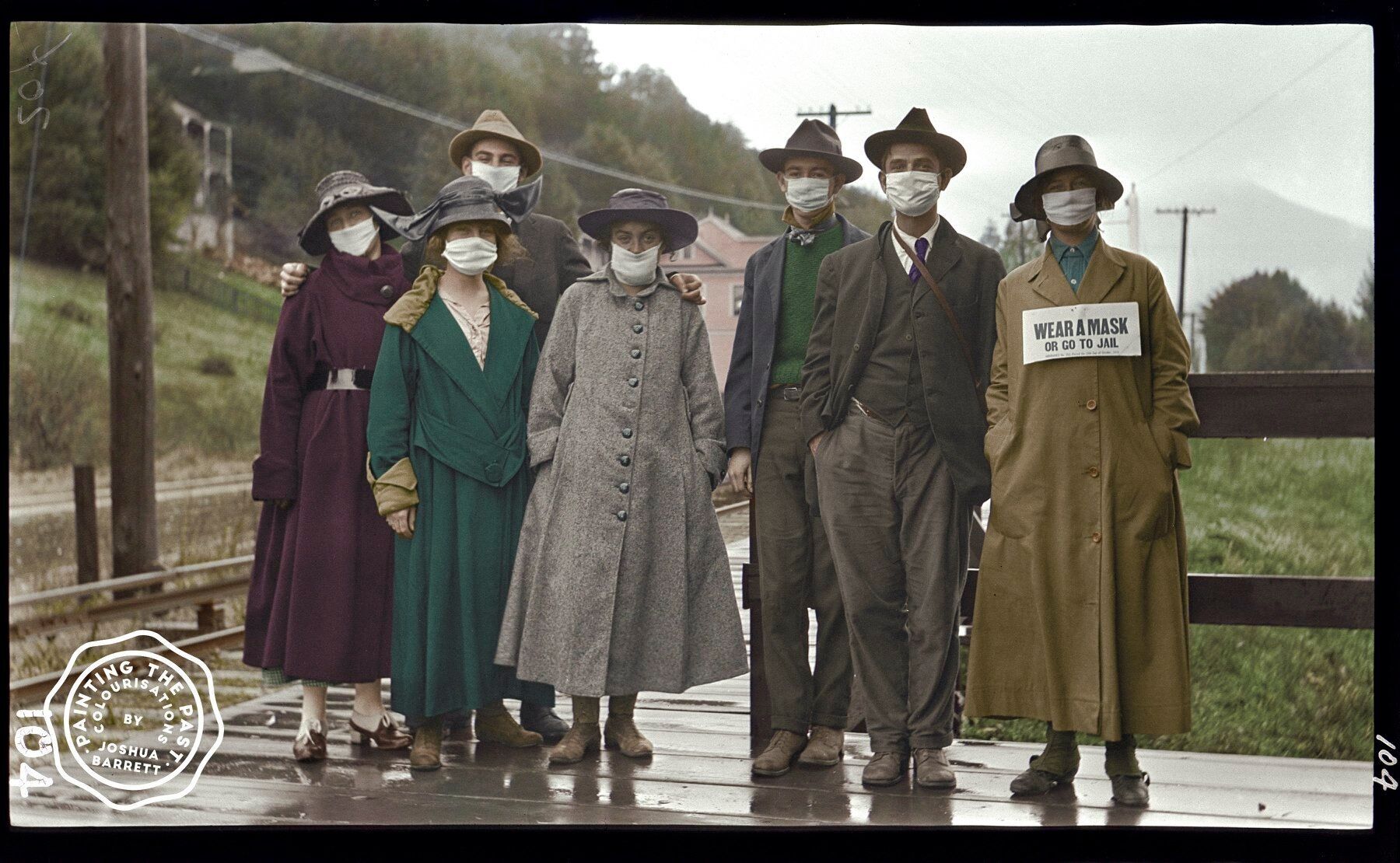 Група молодих людей сфотографувалася на залізничному вокзалі в Мілл-Валлі, Каліфорнія (США), 1918 рік. У жінки справа на шиї табличка, на якій йдеться: "Носіть маску, або посадять у в'язницю"