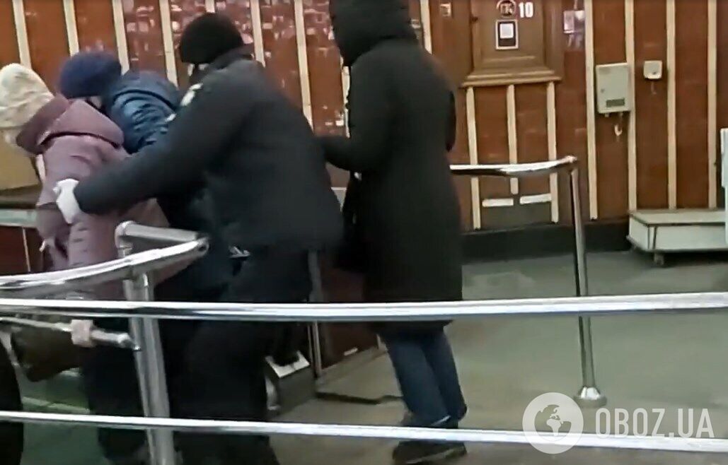 Полицейский пытается оттащить женщину от эскалатора.