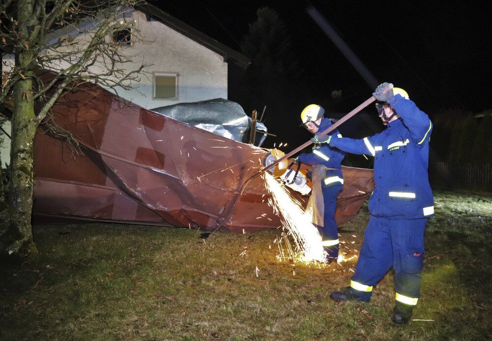Члены пожарной бригады работают на крыше, которая была снесена сильным ветром в Германии