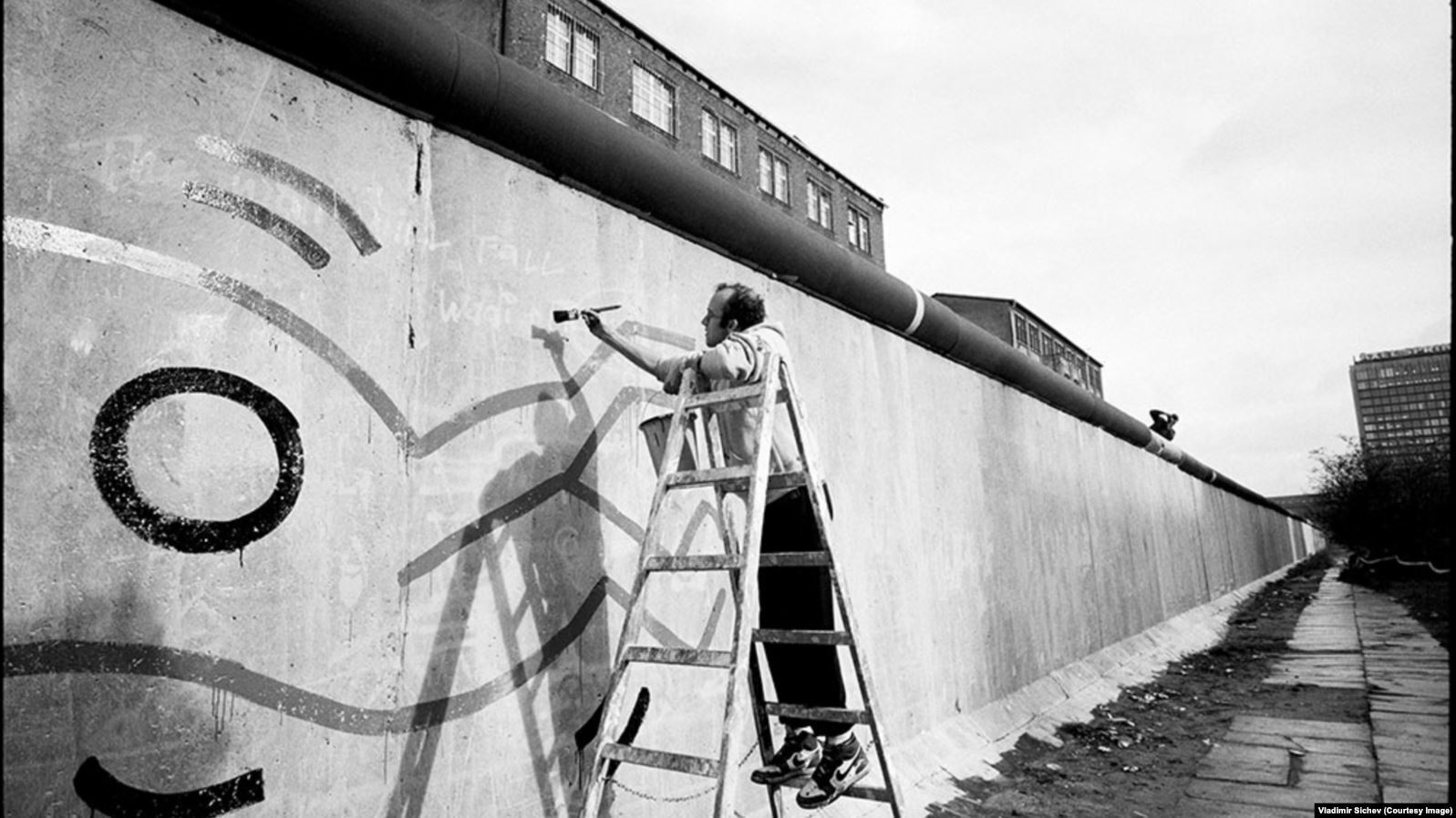 Американский художник Кит Харинг рисует на западной стороне Берлинской стены, 1986 год