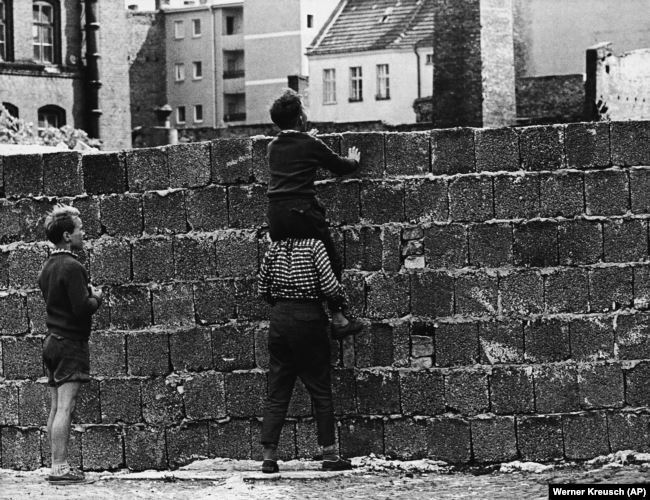 Район Веддінг у Західному Берліні 23 серпня 1961 року. Хлопчик на плечах свого друга дивиться через стіну на квартали в Східному Берліні