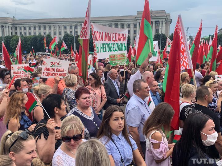 Люди стояли с одинаковыми плакатами и флагами.