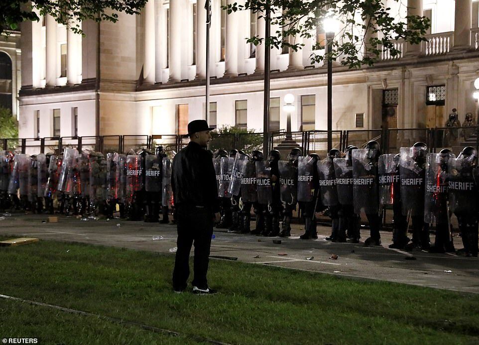 Мужчина стоял перед сотрудниками правоохранительных органов, когда они готовились к столкновению с протестующими