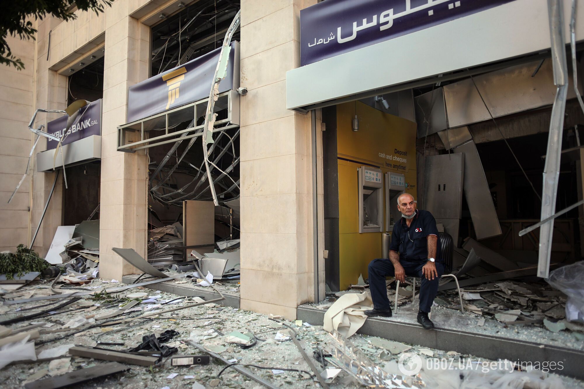 Охоронець сидить біля входу до зруйнованого відділення банку в Бейруті