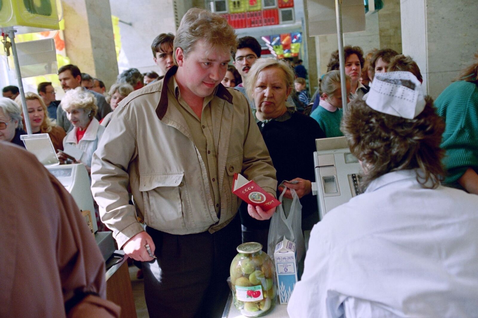 Мужчина показывает кассиру паспорт с московской пропиской, чтобы купить дефицитный товар