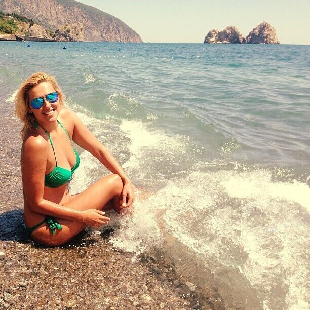 Яна Клочкова в зеленом купальнике возле волн