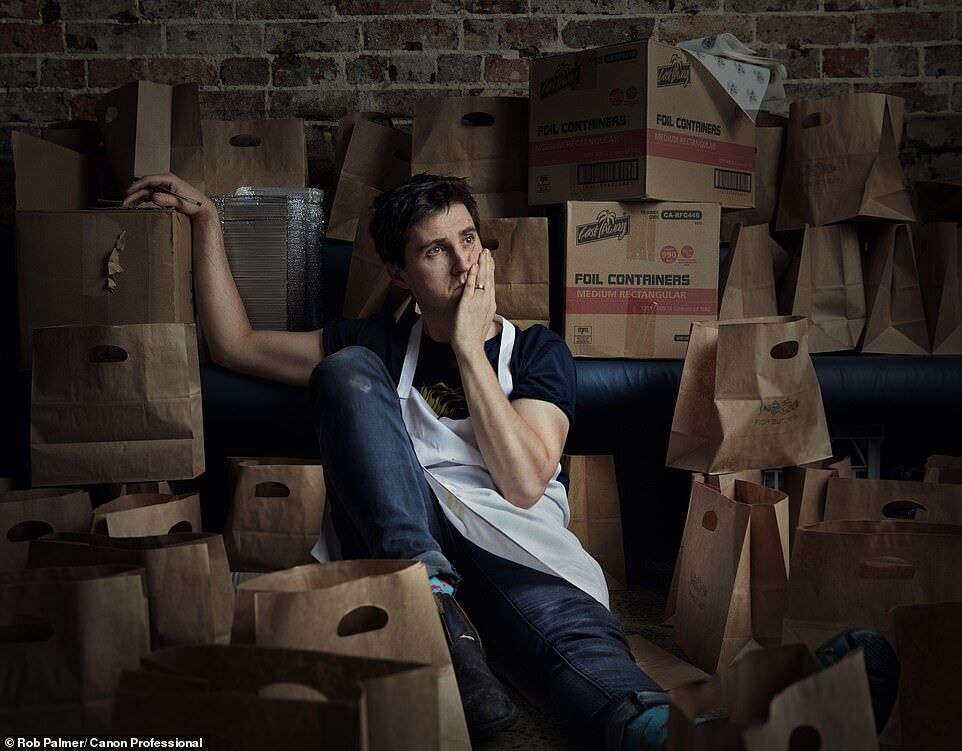 Джош Ниланд из ресторана Saitn Peter среди бумажных пакетов и коробок, предназначенных для еды на вынос