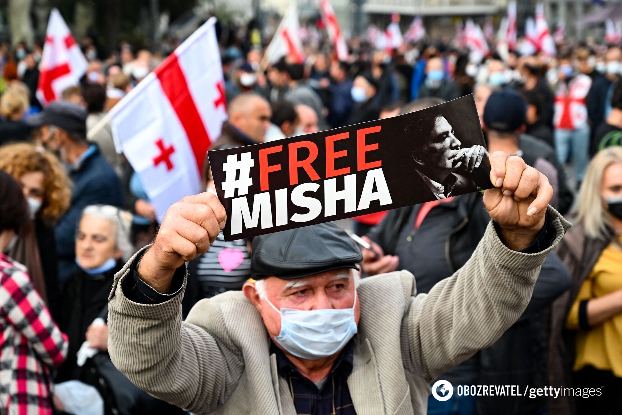 Мужчина держит плакат "Свободу Мише"