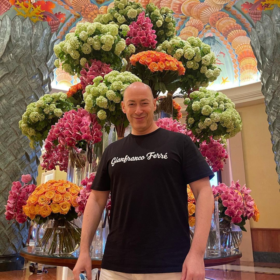 Дмитрий Гордон на фоне цветов.