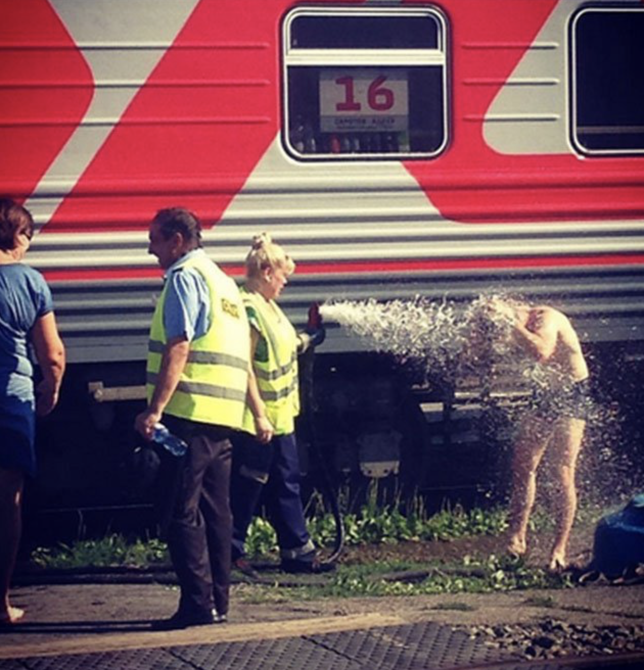 Мужчина принимает душ возле поезда