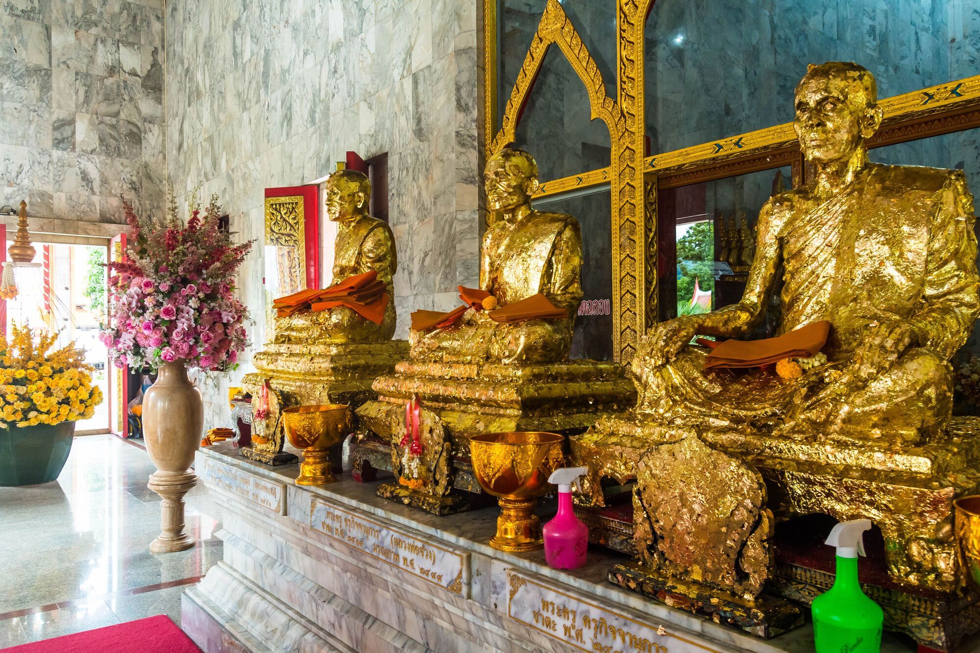 Статуи Будды в храме, украшенные золотистой фольгой.