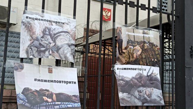 На забор посольства повесили фото с убитыми военными РФ.