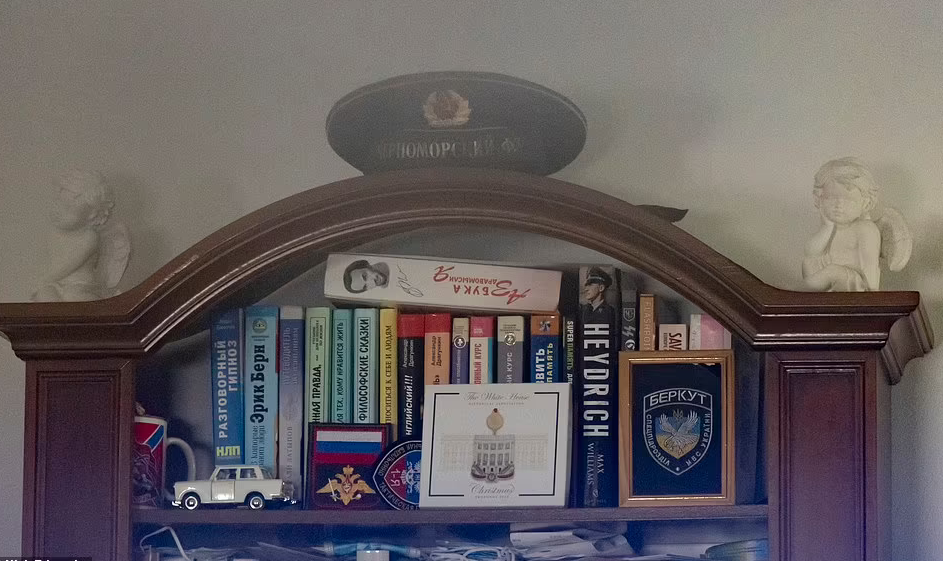 На книжном шкафу – фуражка советского офицера, а на верхней полке - вещи на российскую тематику вместе с нашивкой "Беркута".
