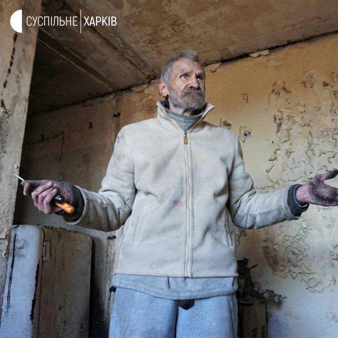 Михаил жил в этом же доме, сейчас он помогает коммунальщикам отыскать останки убитого рашистами соседа