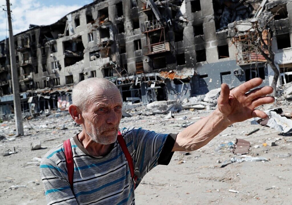 Місцевий житель жестикулює біля зруйнованої будівлі
