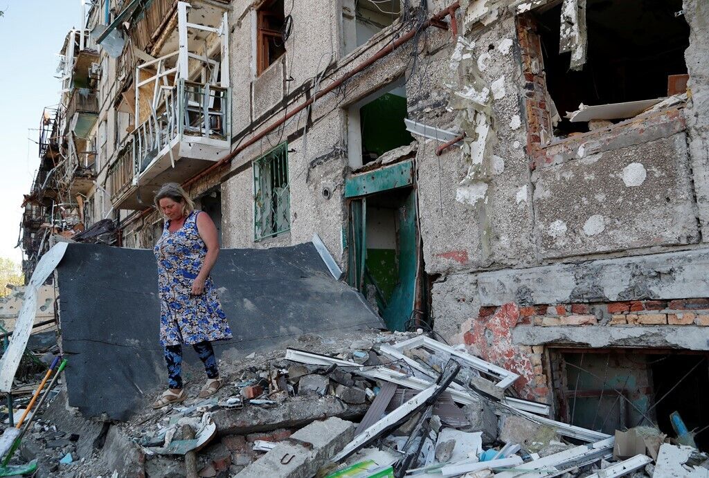 Женщина на обломках жилого дома после бомбардировок