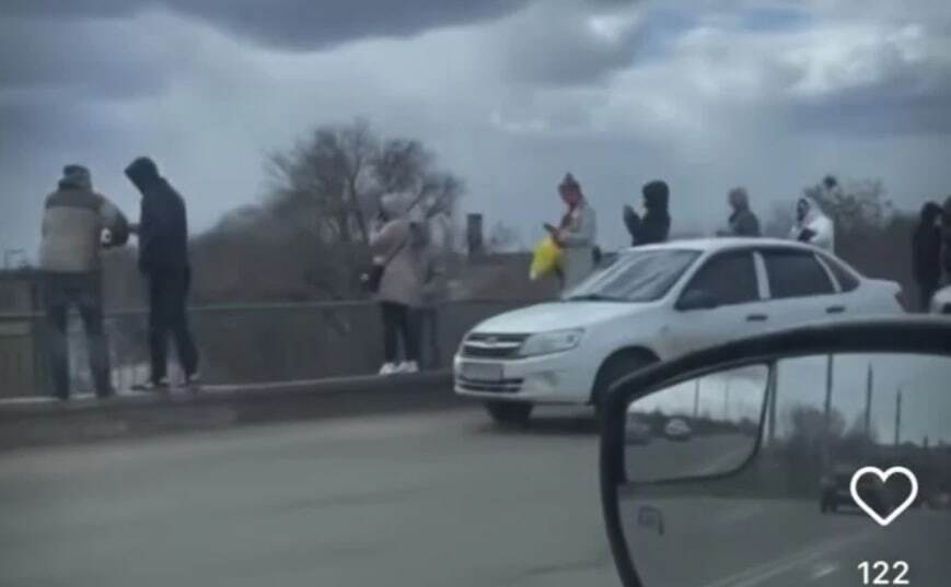 Люди ищут сигнал мобильной сети на мосту на Новый Мелитополь