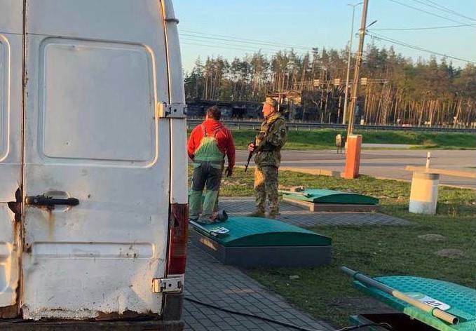 Мужчина сливал топливо из резервуаров заправки в бочку.