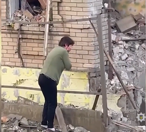 Женщина плачет возле своего разрушенного дома