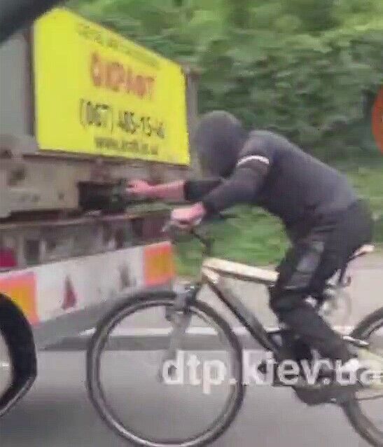 Велосипедист держался рукой за прицеп грузовика.