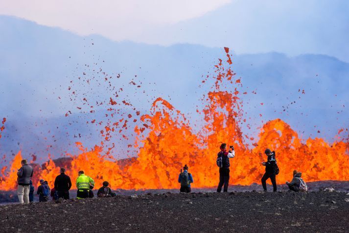 Люди смотрят на извержение вулкана Фаградальсфьядль в Исландии