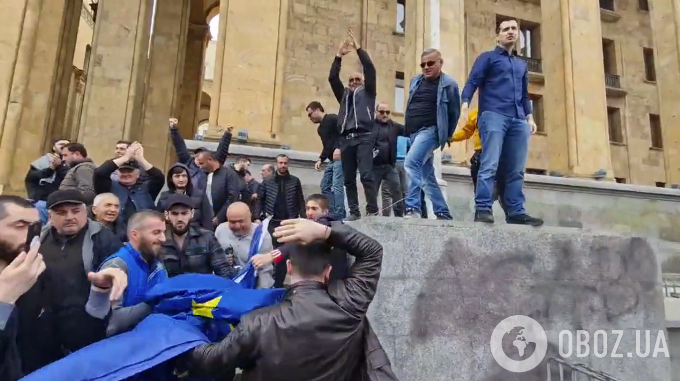 Протестующие сорвали флаг, после чего стали его топтать