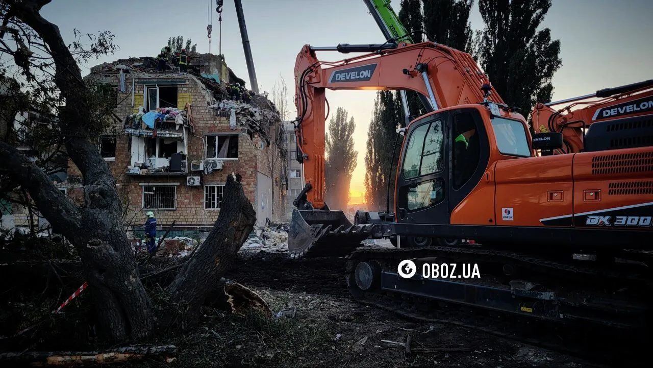 "Не втрачають надії": у Києві під прожекторами розбирають завали на місці удару РФ, люди приносять іграшки у пам'ять про загиблих дітей. Фото та відео
