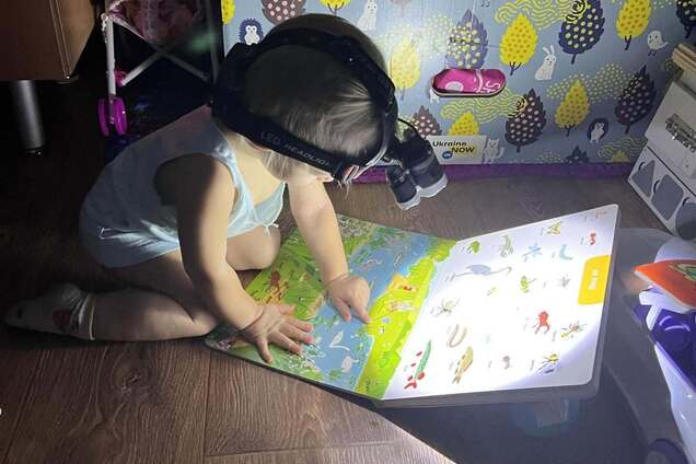 Навчання триває попри все: українська дитина у темряві з ліхтариком читає книжку через російський теракт. Зворушливе фото