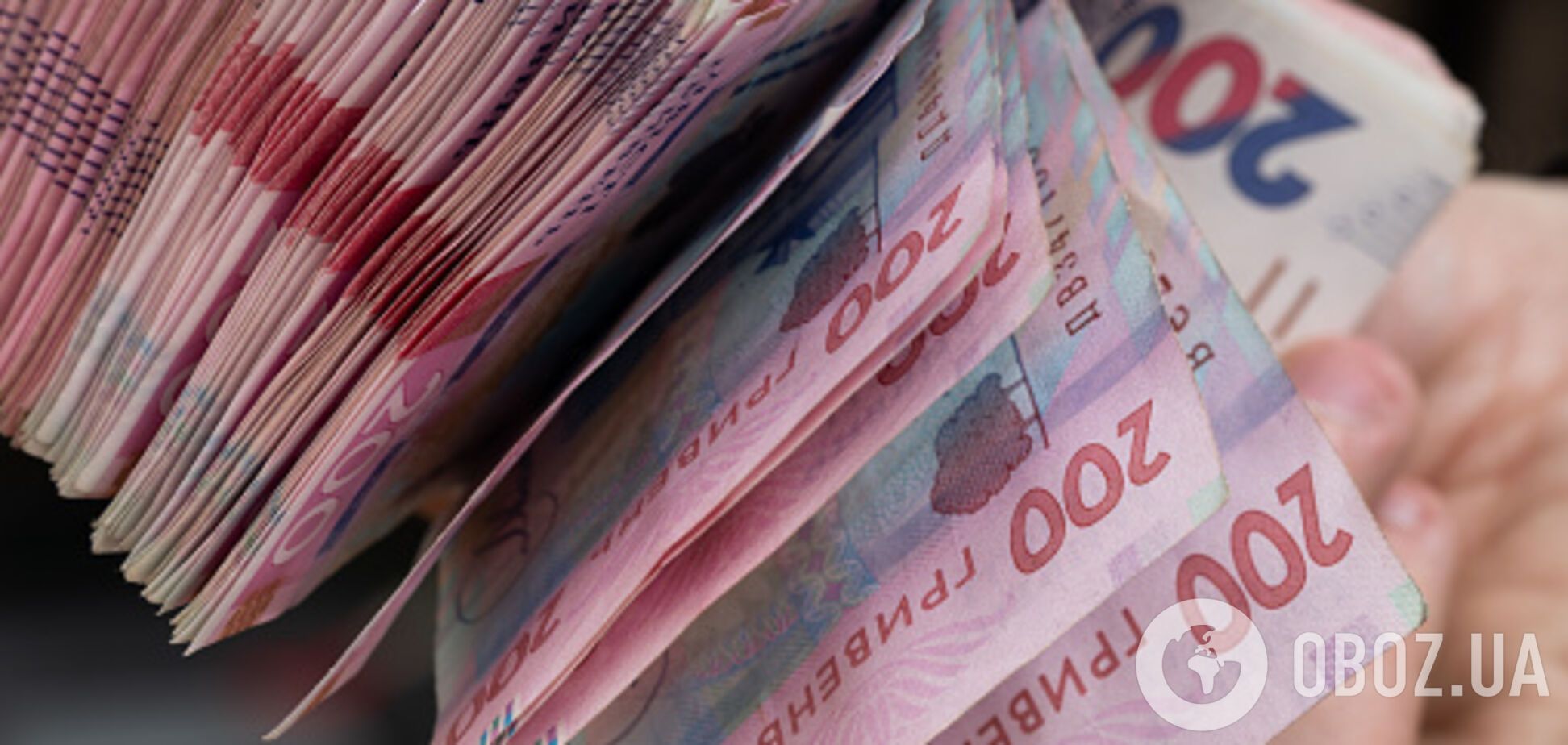 Иллюстративное фото. Купюры по 200 украинских гривен в руках, пачка денег