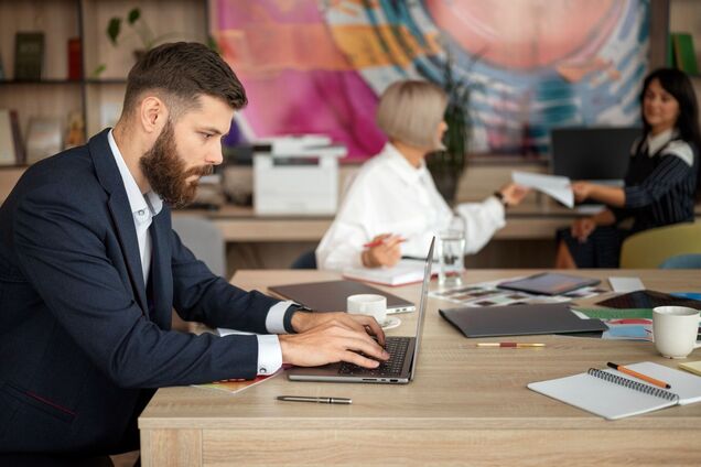 Ілюстрація - офісні роботіники, чоловік працює за ноутбуком