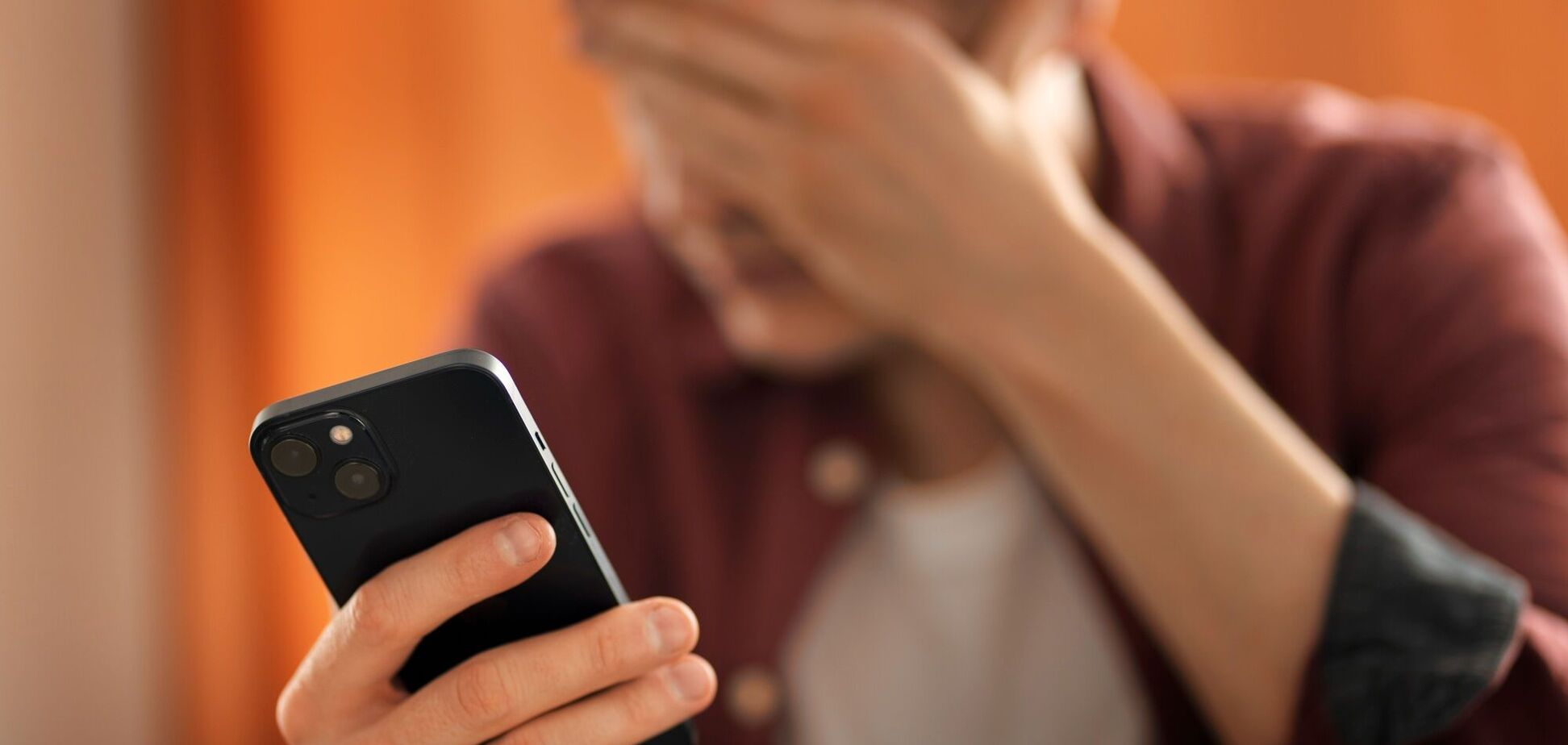 Ілюстрація - чоловік тримає мобільний телефон і закриває обличчя