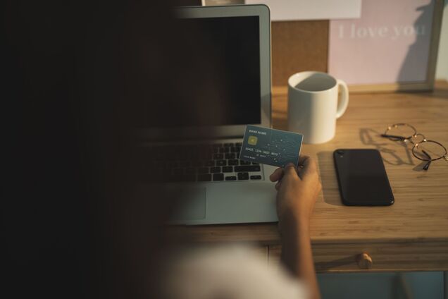 Девушка с банковской картой за ноутбуком. Иллюстрация