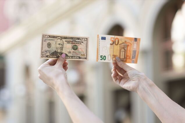 Купюри 50 доларів і 50 євро в руках. Ілюстрація